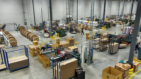 An aerial ivew of an industrial facility's interior shows equipment and fiber packaging on the manufacturing floor.