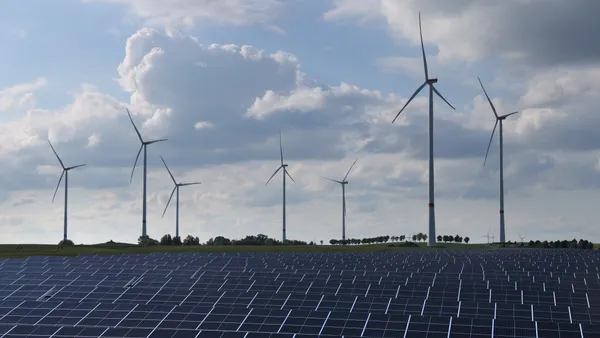 Wind turbines spin behind a solar energy park.