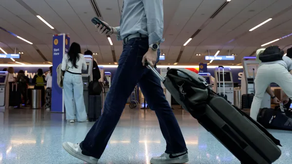 A man rolls his suitcase through an airport terminal.