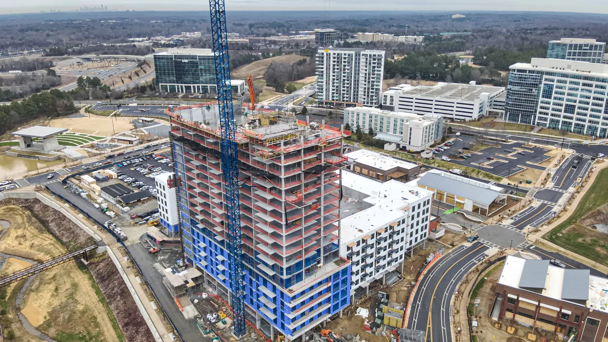 An elevated view of a crane over a tower under construction.