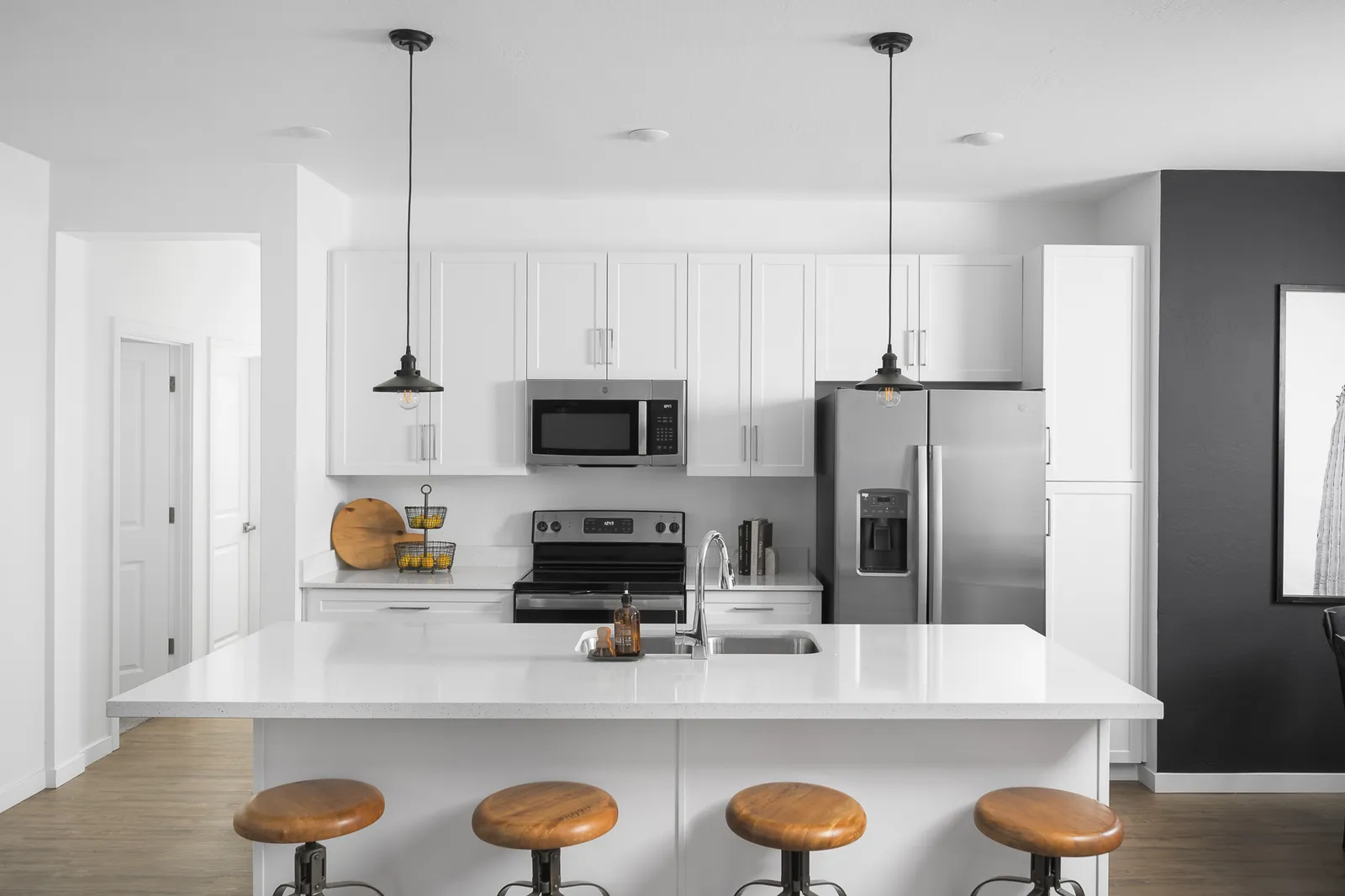 A white kitchen with stainless steel appliances and a kitchen island with seating.