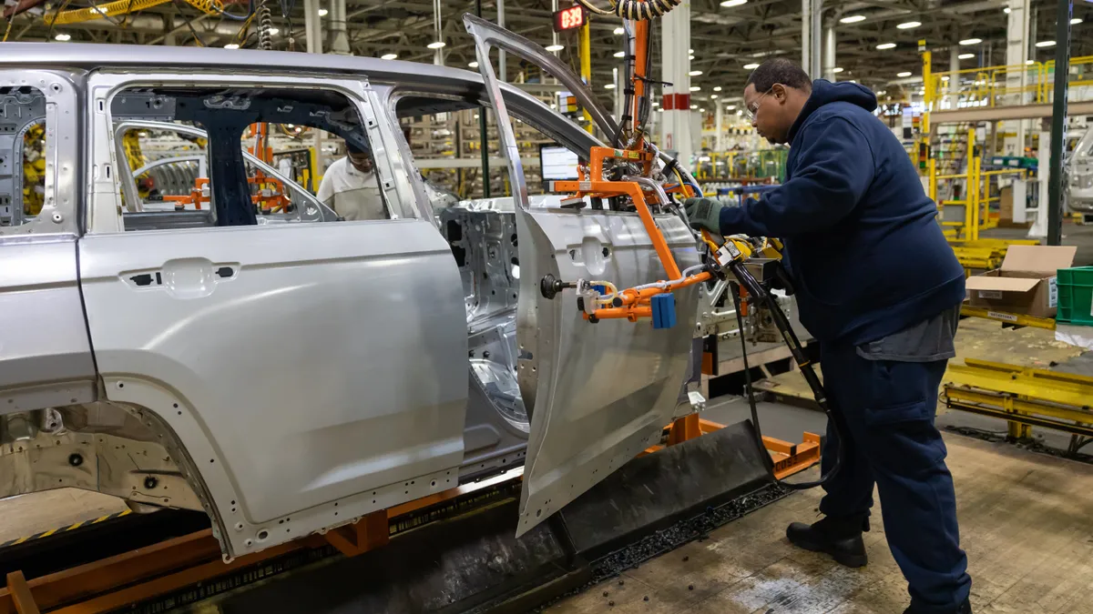 A production operator installs a Jeep Grand Cherokee door.