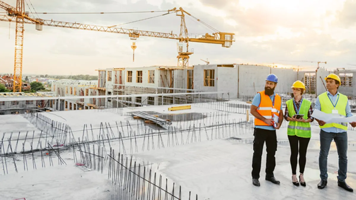 Construction team working on a roof with large equipment in background