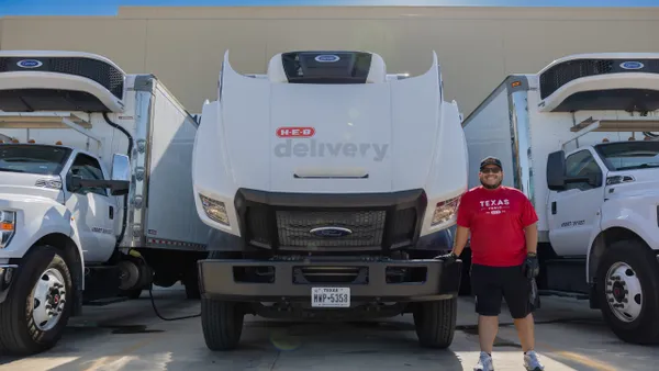 A person in front of a white "H-E-B delivery"-branded vehicle.