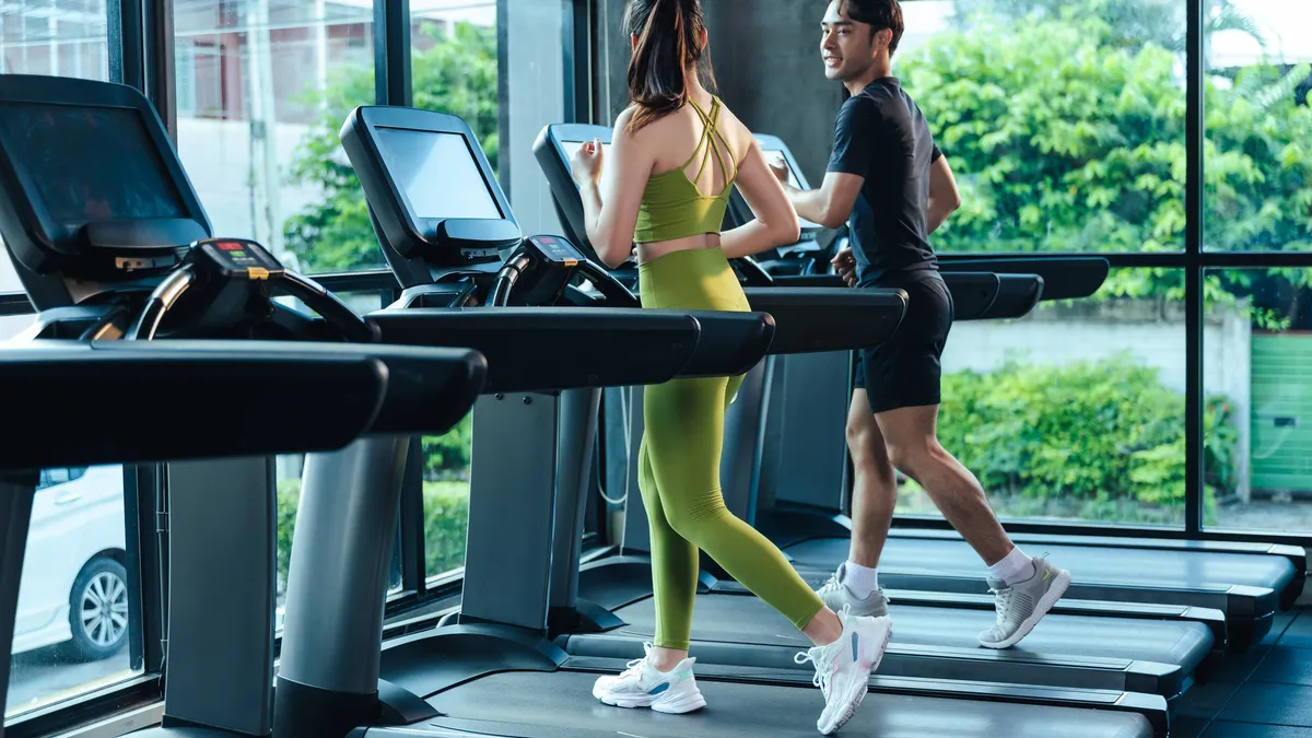 a man and woman walk on treadmills in an apartment gym