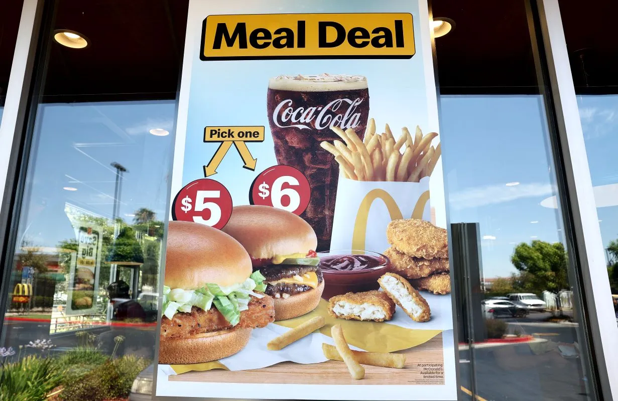 Am image of a sign on a window that says "Meal Deal" and shows a chicken sandwich and burger with nuggest, fries and a Coca-Cola.