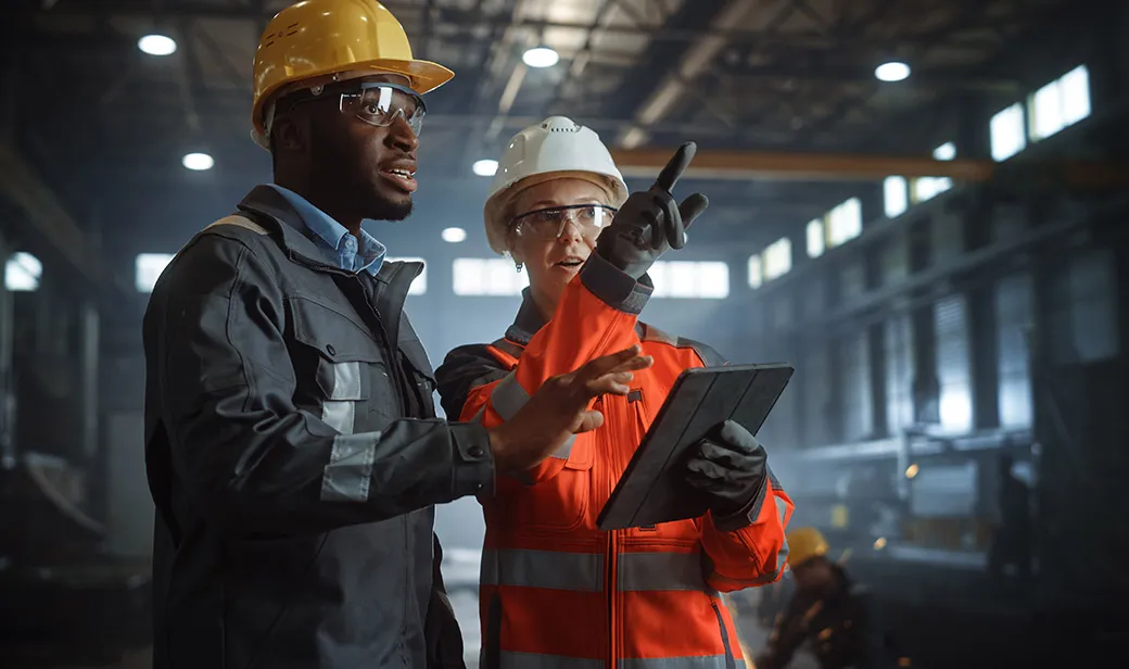 Two Heavy Industry Engineers Stand in Steel Metal Manufacturing Factory, Use Digital Tablet Computer and Have a Discussion.