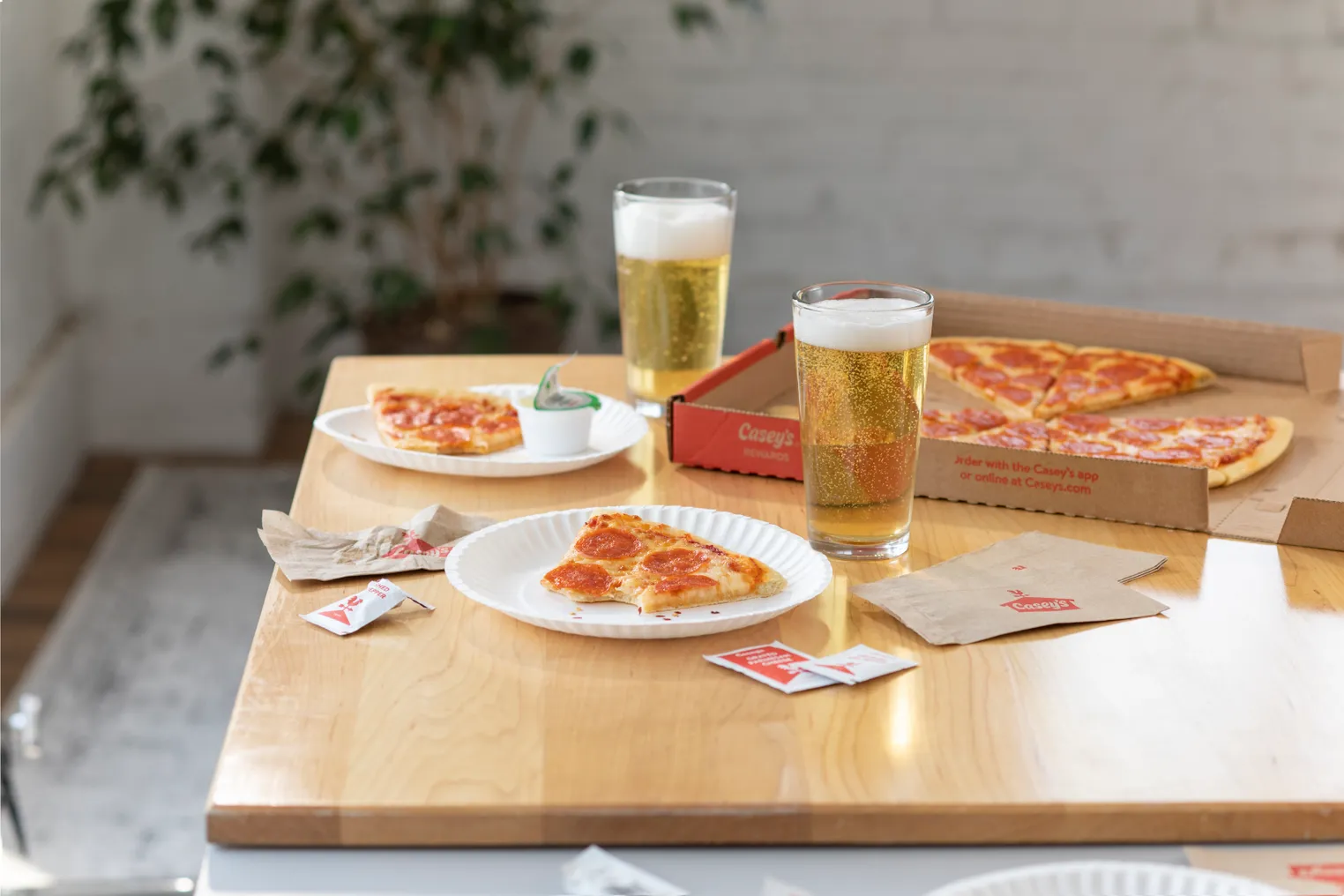 A photo of a meal consisting of pizza and beers on a wooden table.