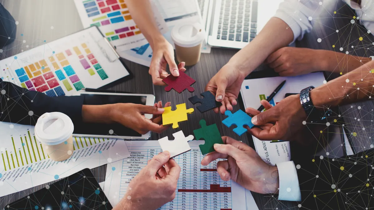 A bunch of hands trying to put a puzzle together on a desk.