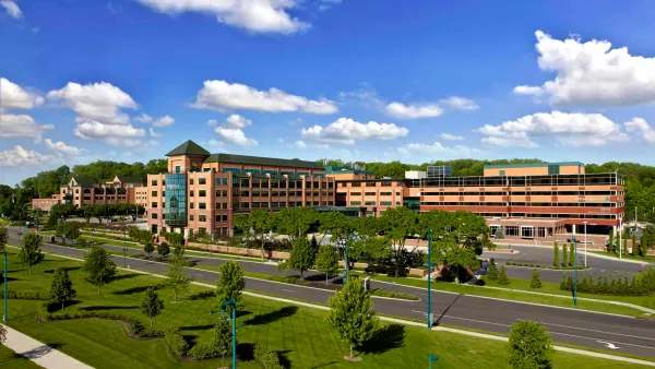 Wide-angle view of Kettering Health Medical Complex on a sunny day, featuring multiple connected buildings surrounded by lawns and trees.