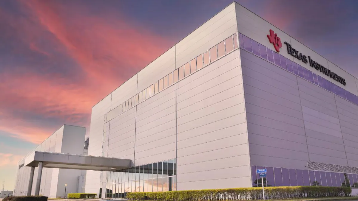 A an external corner of beige and iris purple building with the red and black Texas Instruments logo.