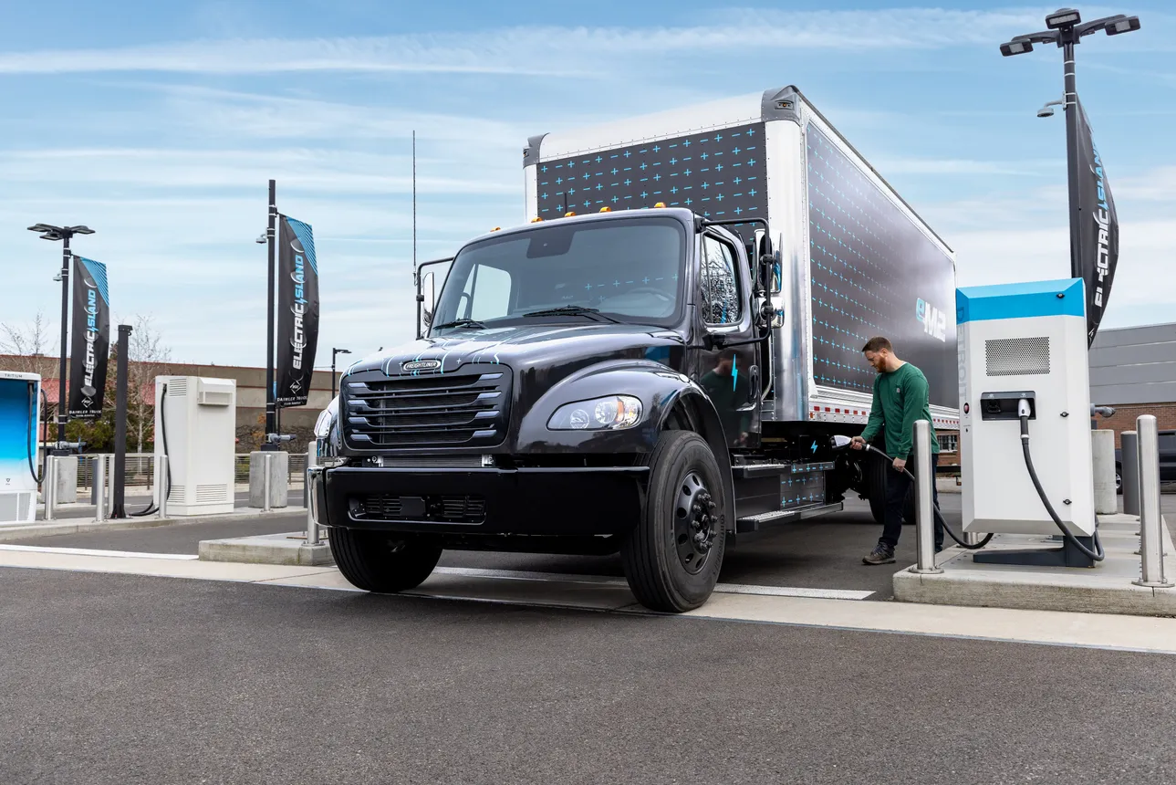 A driver charges a Freightliner eM2 medium duty battery-electric truck.