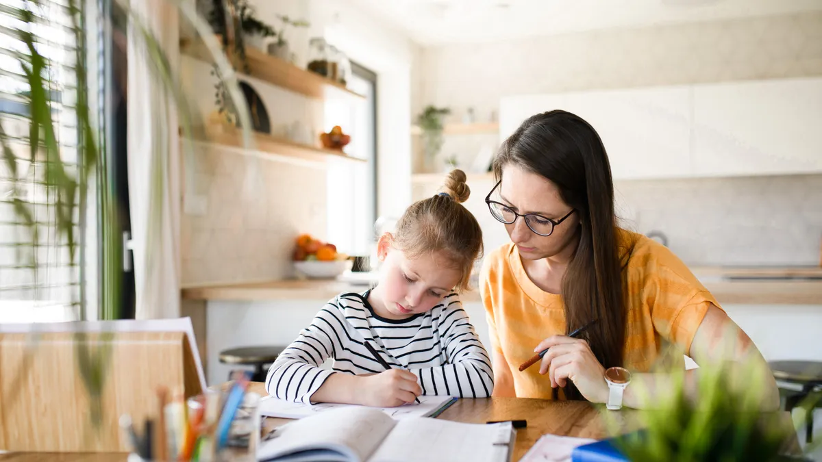 A mother teaches her daughter at home.