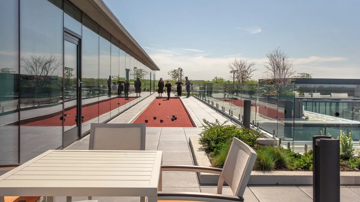 A bocce court is set up and awaiting players on a rooftop lounge of an apartment building