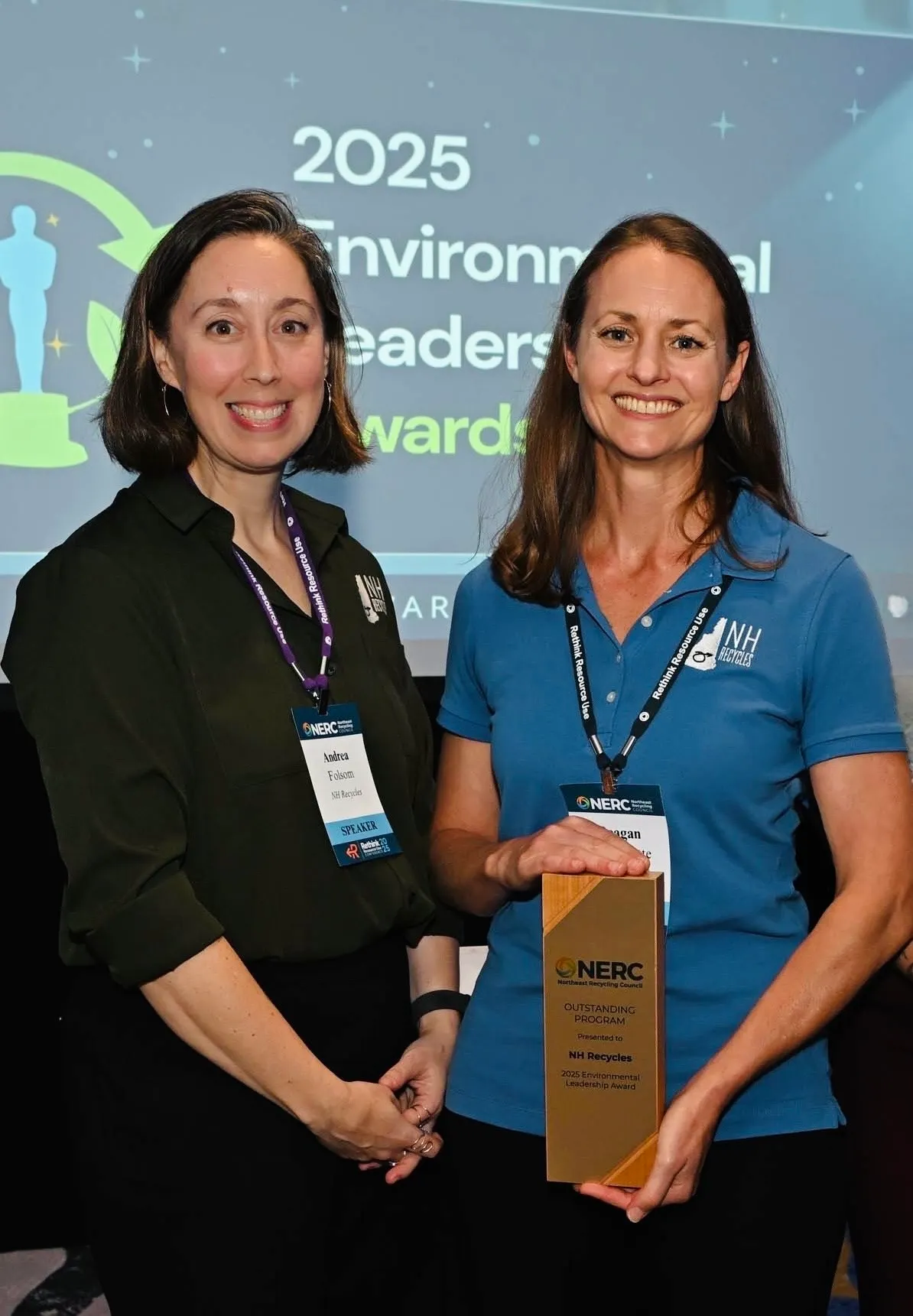 Two women stand together holding an award