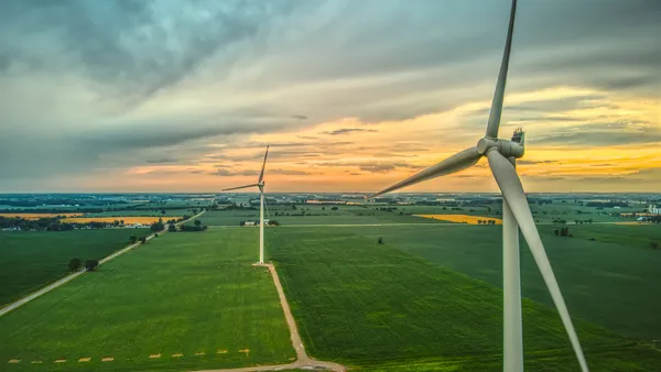 An aerial image of two wind turbines in rural farmland at sunset in Southwestern Ontario, Canada