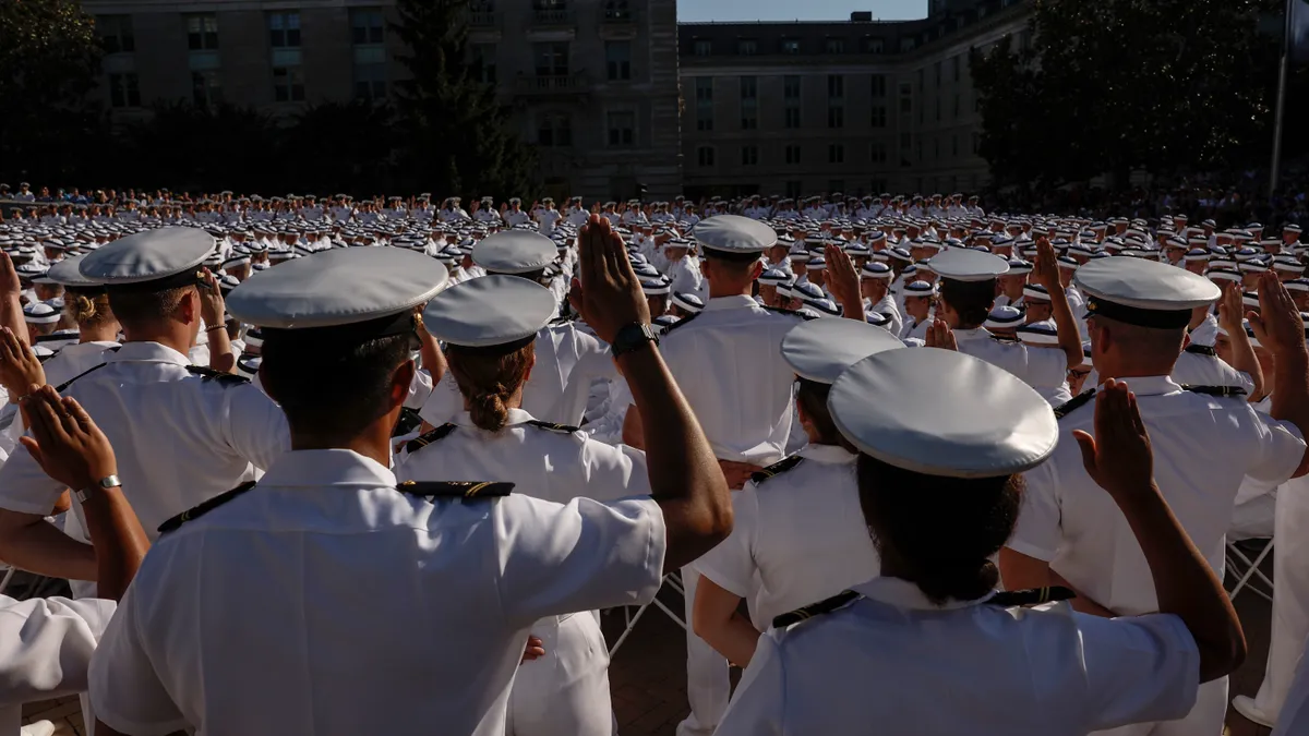 Rows of cadets facing away from the camera salute