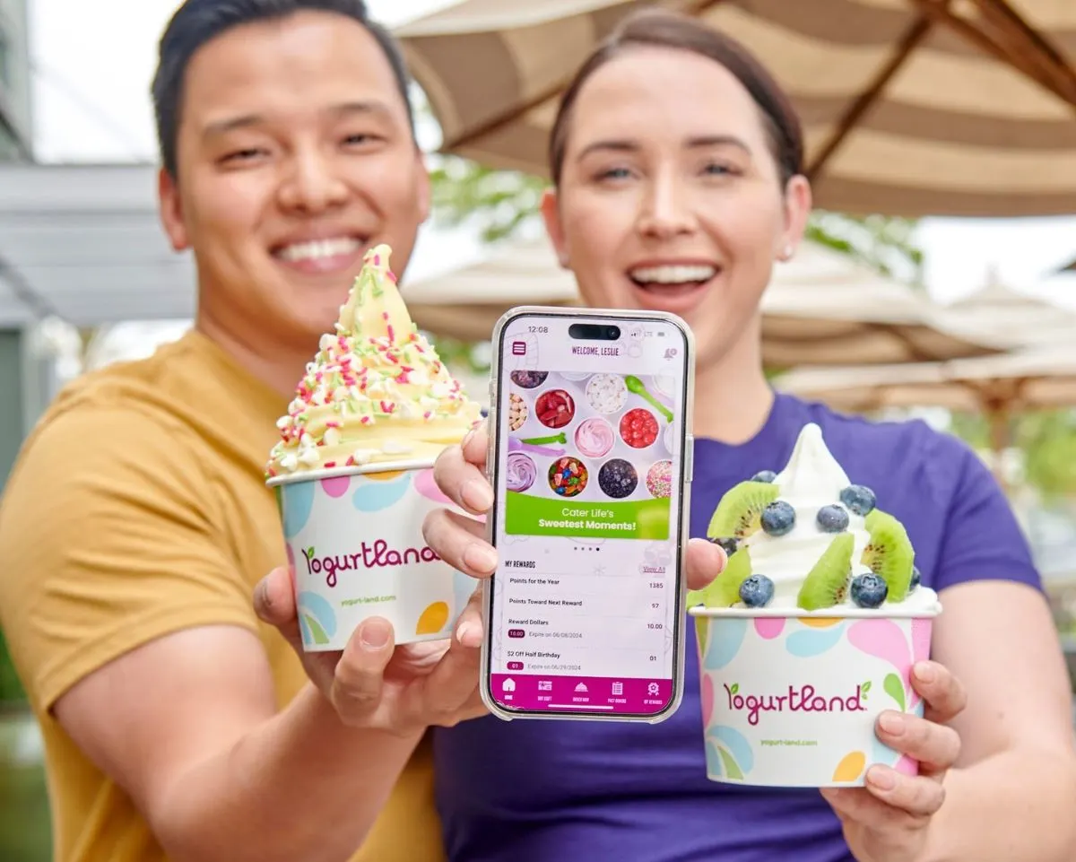 An image of two people with bowls of frozen yogurt. The person on the right is holding up a phone with Yogurtland app.