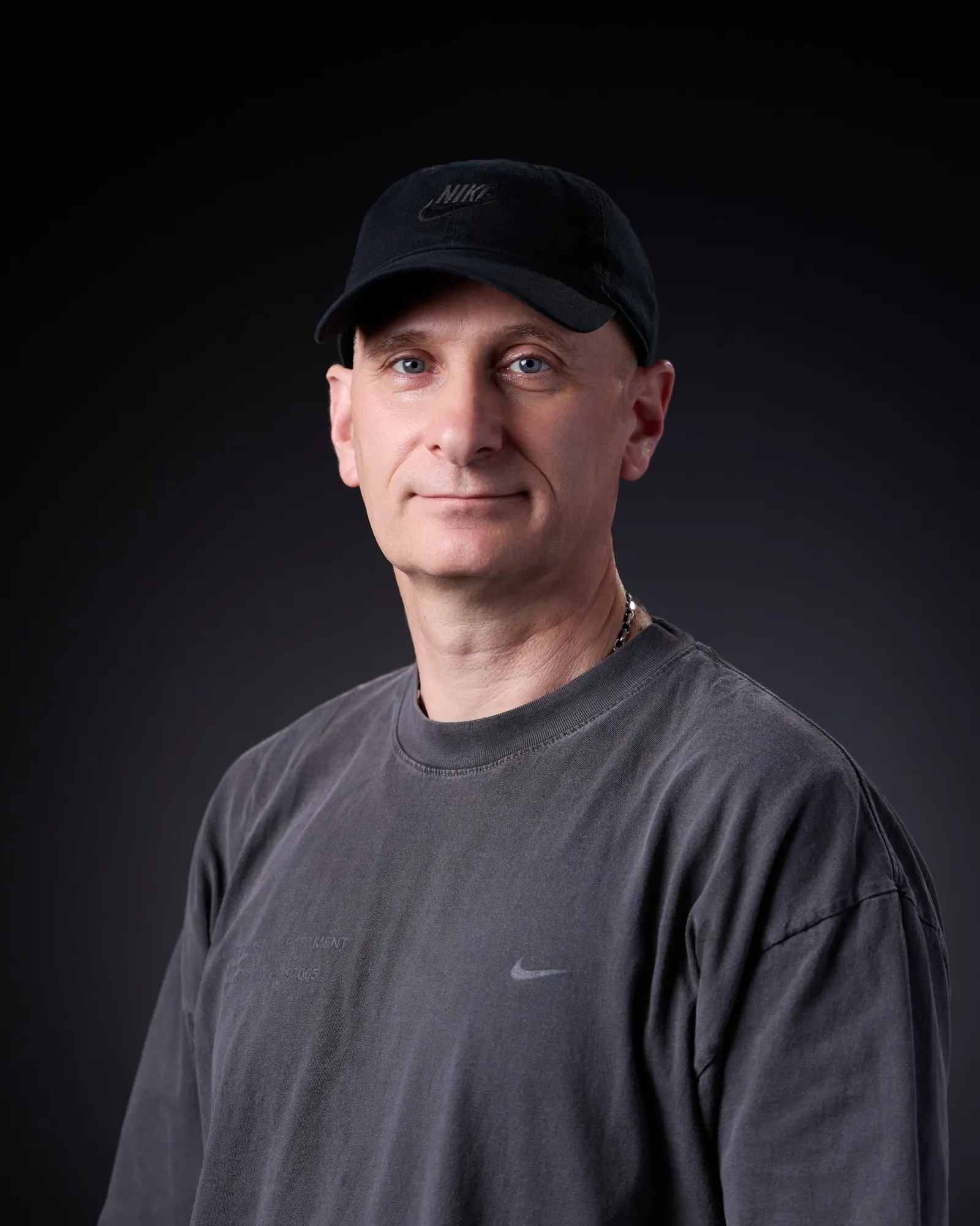 A headshot of Andy Caine in a black Nike T-shirt and hat.