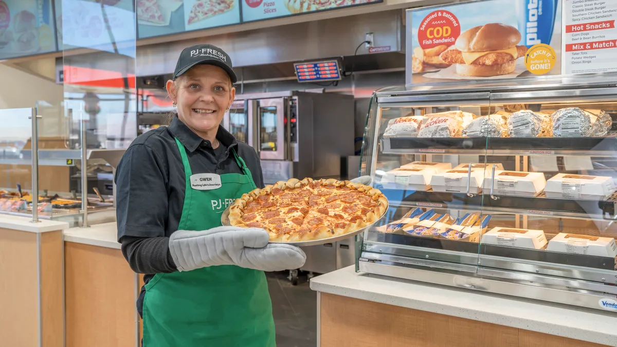 A Pilot employee showcases fresh pizza at one of the company's updated stores.