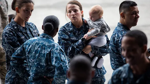 Military members in blue camouflage, one holding a baby.