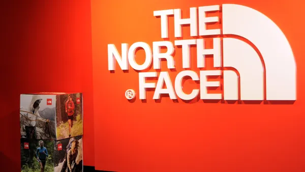 A large orange wall features the words The North Face printed in white.