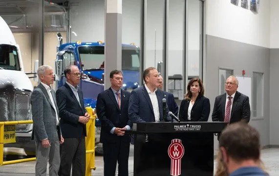 Officials gather at a dealership in Indiana around a podium.
