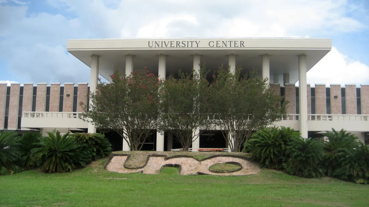 UNO University Center as seen from the front, with shrubs in the foreground and "UNO" spelled out with stone in the grass.