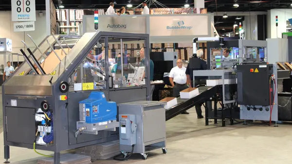 An industrial scale machine for manufacturing packaging is displayed at the Pack Expo trade show.