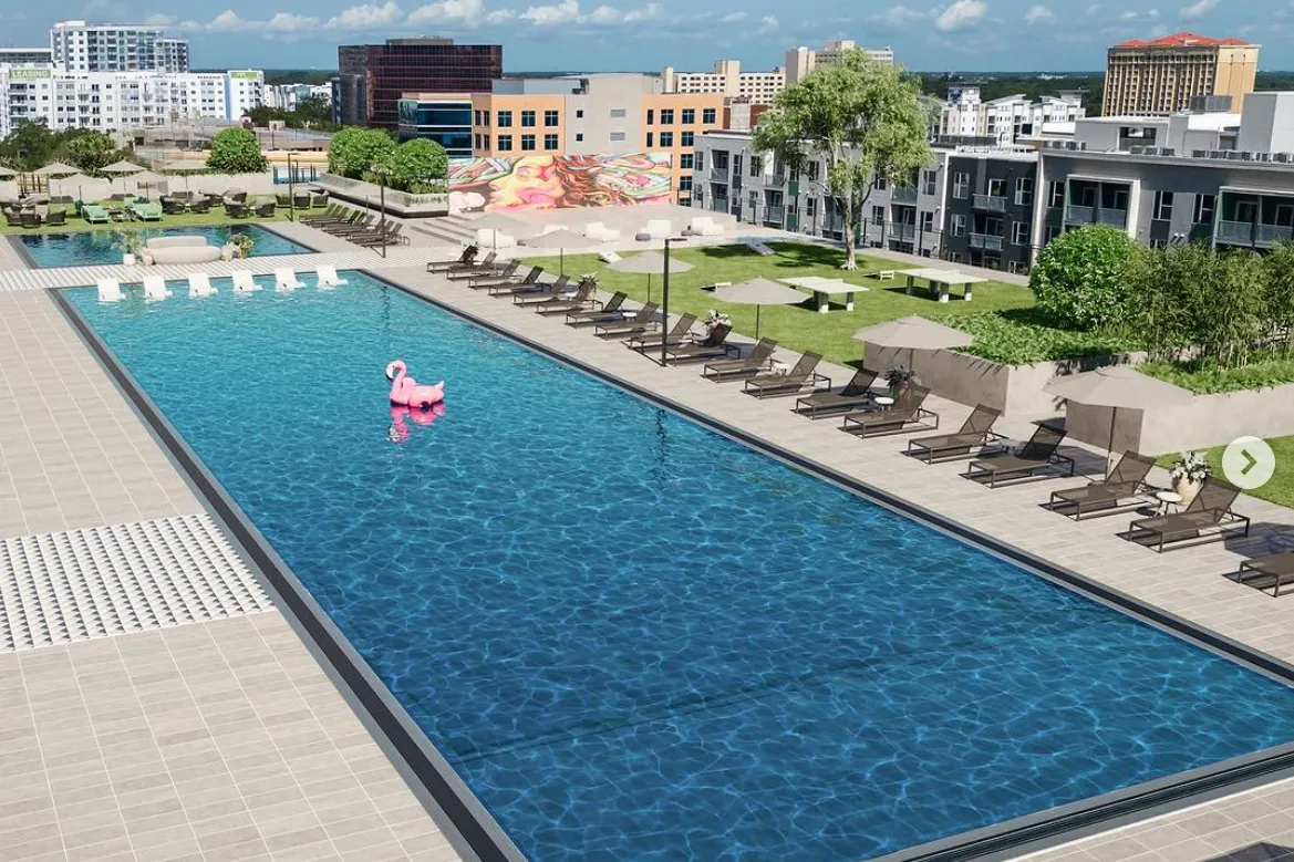 A pool area with lounge chairs and a pink flamingo floatie.