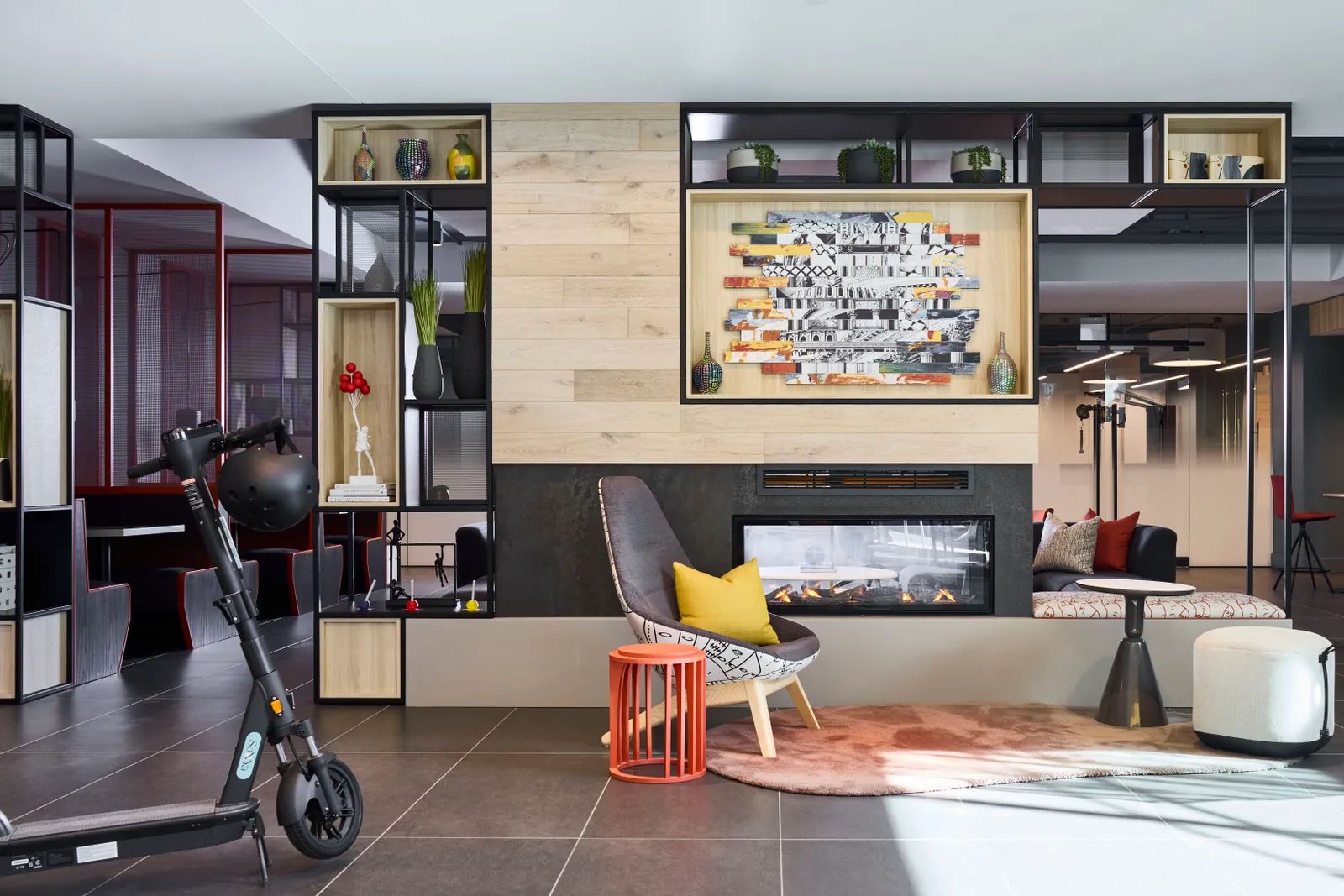 A room with chairs, a bookshelf, a fireplace, and an electric scooter in the foreground.