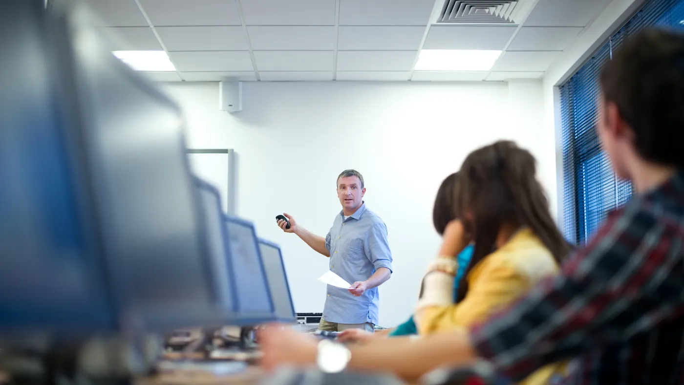 Students sit at computer terminals in a classroom.