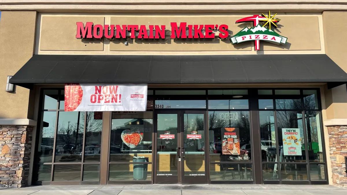 A beige storefront with a bank of windows in the front. The top of the buildings sayd "Mountain Mike's