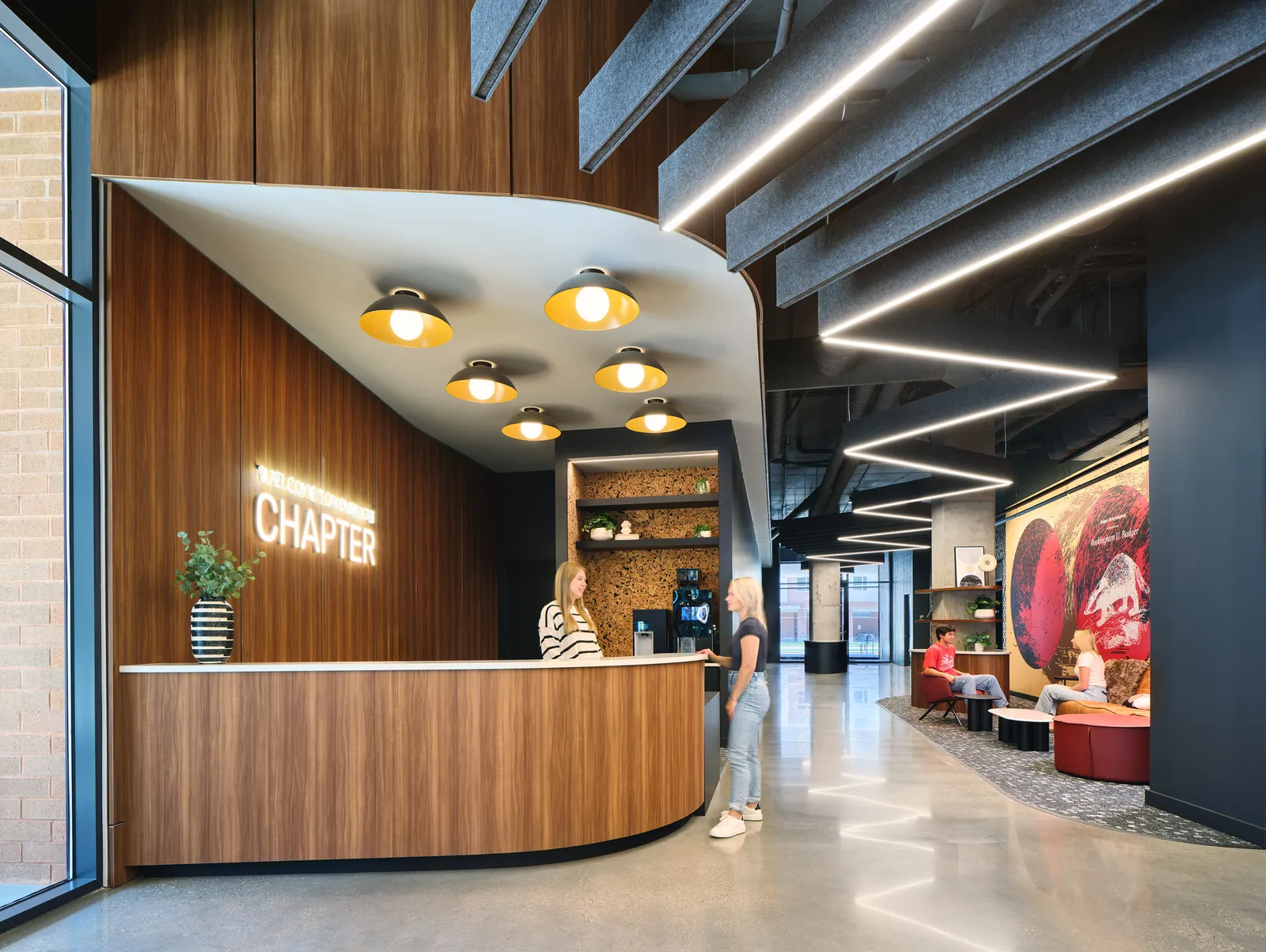 A tall building lobby with two people talking to each other.