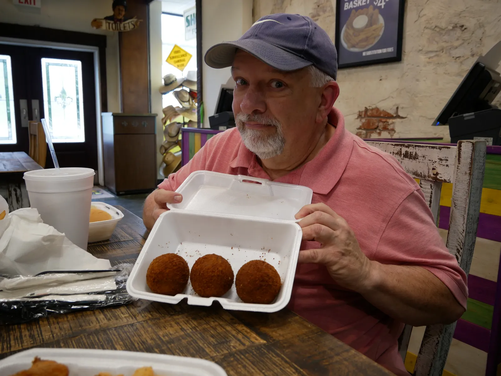 A photo of a person holding a styrofoam package of food inside a dining room.