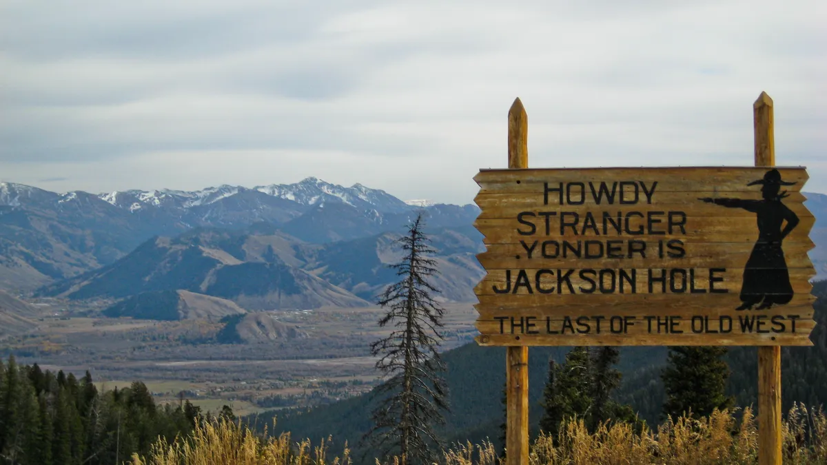 The sign reads "howdy stranger yonder is Jackson Hole, last of the old west. On top of Teton Pass Wyoming