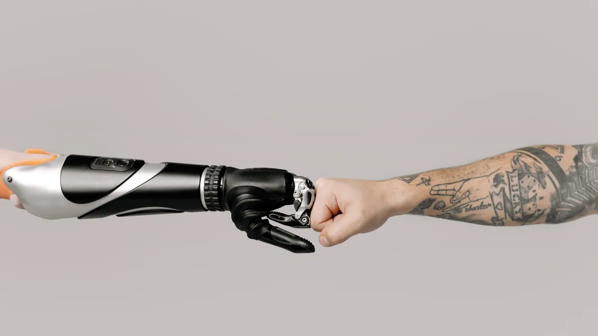 A prosthetic arm and a tattooed arm fist-bump