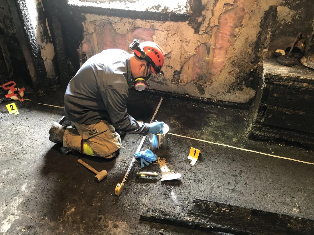 A man collects evidence at the scene of a fire