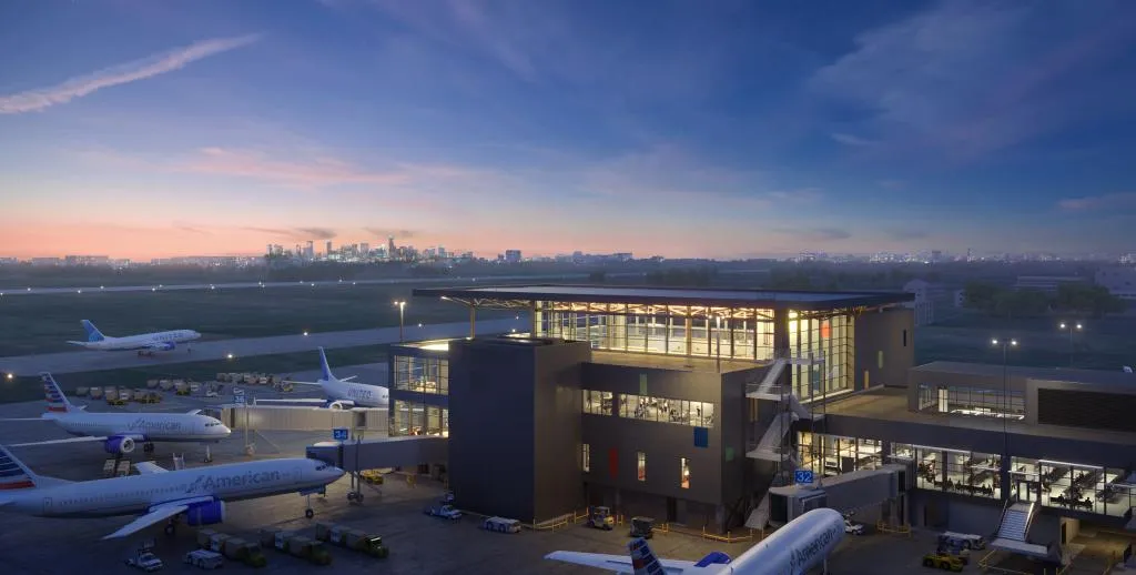 Nighttime view of a glassy building surrounded by airplanes.