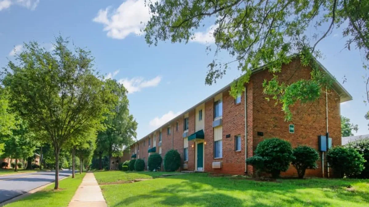 Brick apartment with grass in the foreground.