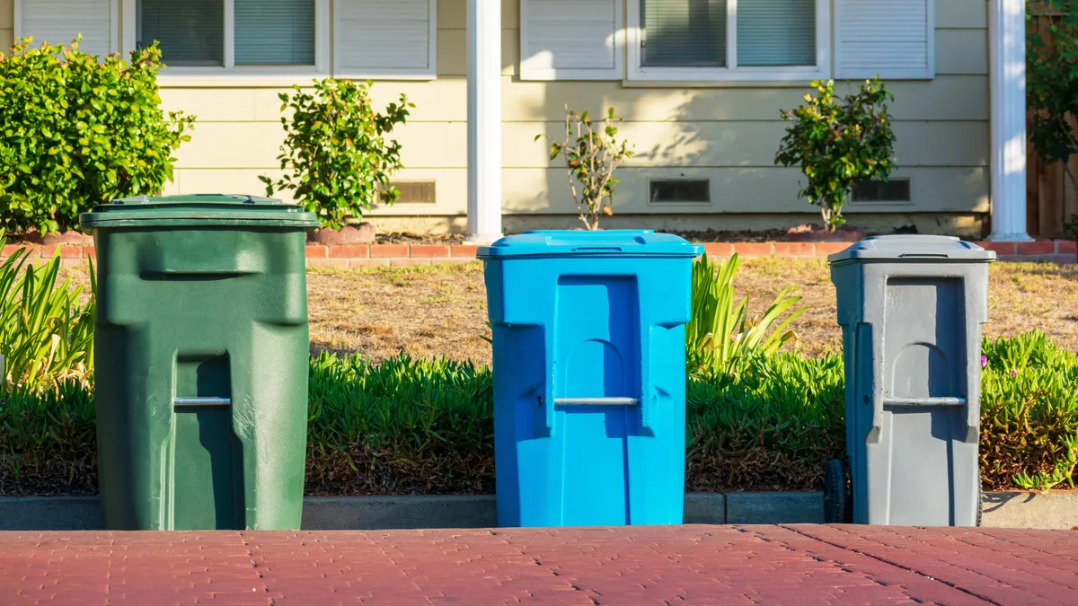 Compost, recycling and garbage carts set outside of the home on the curb for residential garbage and recycling pickup.