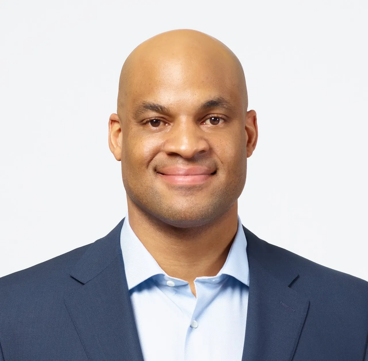 A person with a bald head wearing a jacket and shirt but no tie.