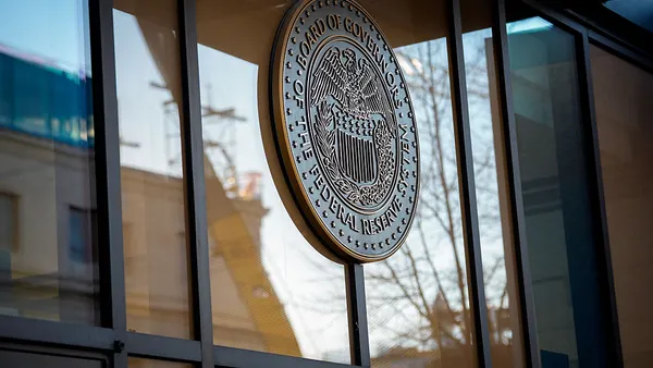 A Federal Reserve logo sign is shown affixed to panes of glass on a building's exterior.