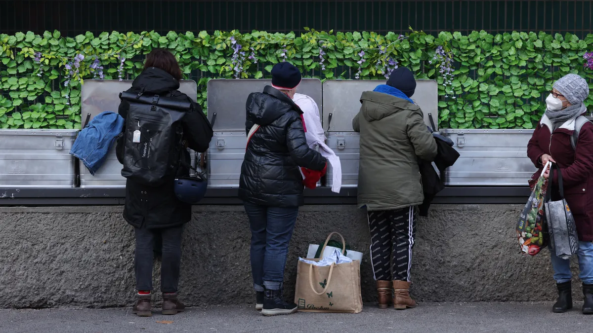 People dressed in warm clothes look among donated items left in bins.