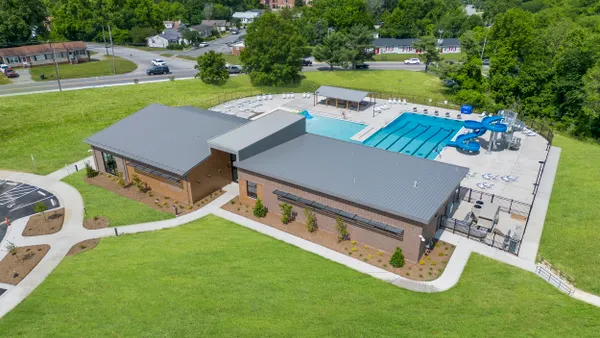 Aerial view of a one-story brick building with pools and slide behind it.