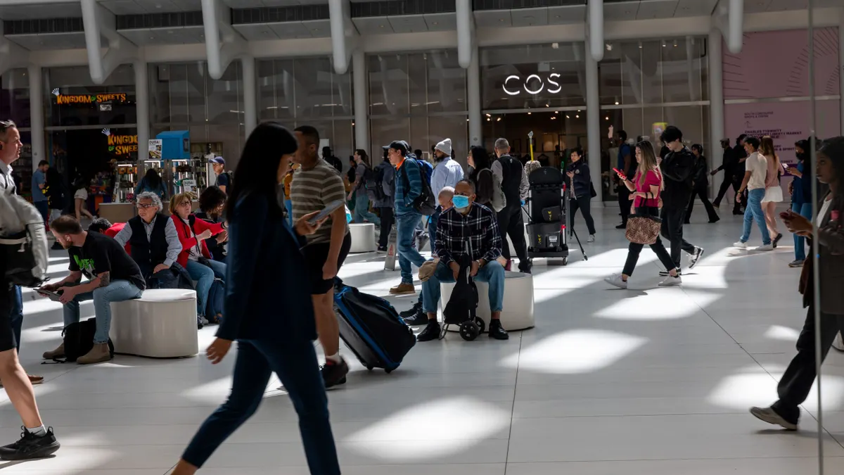 Many people walk through a transportation and shopping hub.
