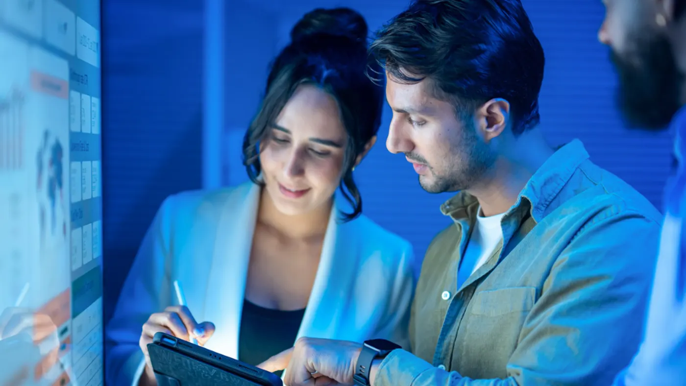 Two coworkers working on an iPad together in a blue colored room