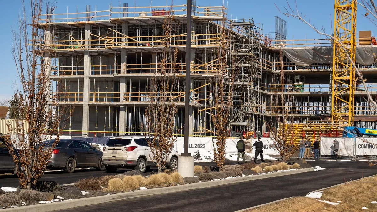 First responders gather around a scaffolding-covered building.