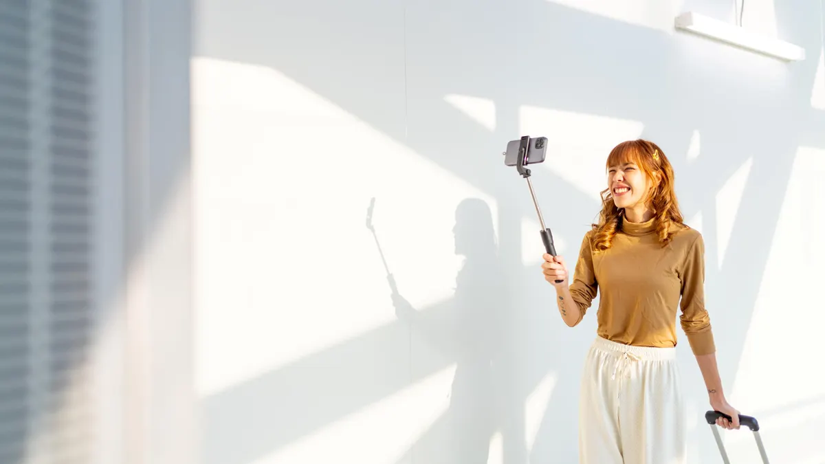 An influencer records a video with a smartphone selfie stick while outside