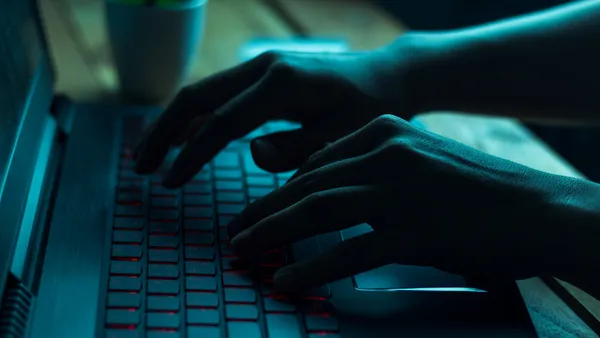 A person types on a laptop in a dark room.